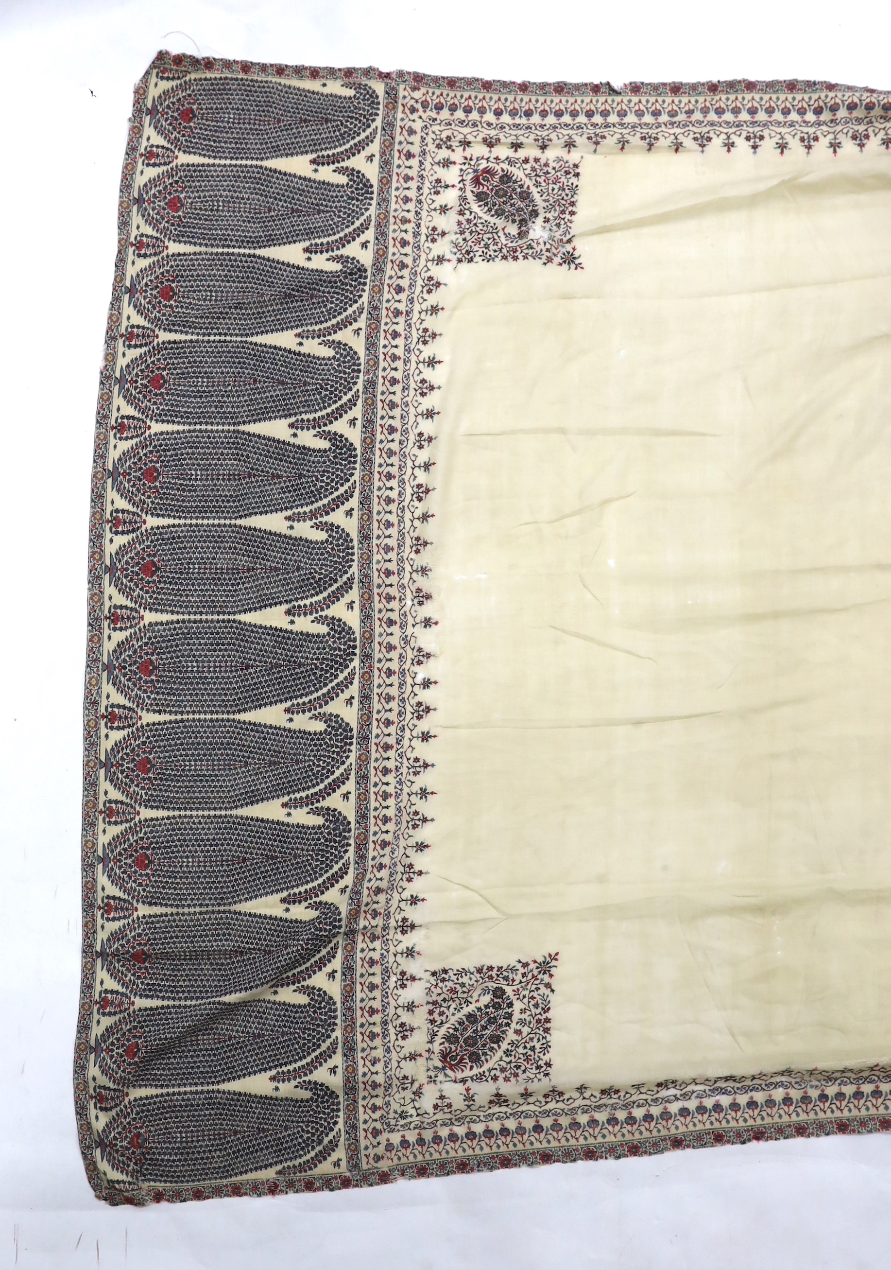 A 19th century fine cream woven Kashmiri shawl with blue and red teardrop design borders, an early 20th century gold satin pelmet with spot motifs of peacocks and flowers, 204cm long x 71cm high and a length of silk with